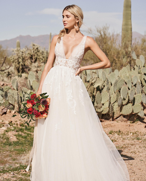 Model in the dessert wearing a boho wedding dress made of soft tulle with a double band waist. Made by Lillian west and available at Brides Of Southampton